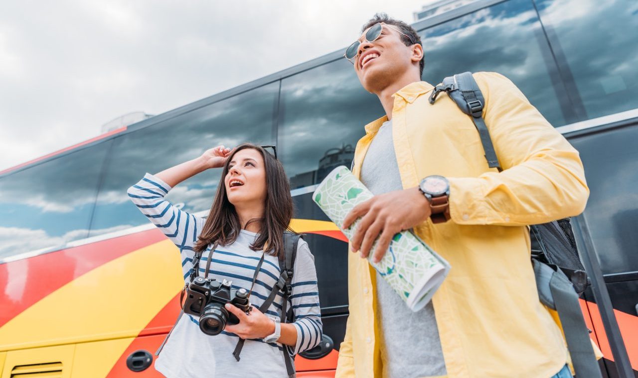 woman-holding-digital-camera-and-looking-away-with-mixed-race-man-holding-map-near-travel-bus.jpg